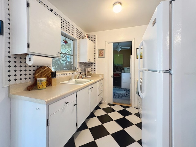 kitchen with light floors, washer / clothes dryer, light countertops, freestanding refrigerator, and a sink