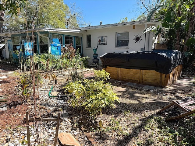 back of property with stucco siding and a hot tub