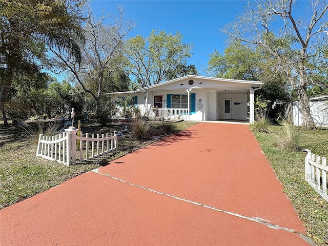 view of front facade featuring driveway, a porch, fence, and an attached carport