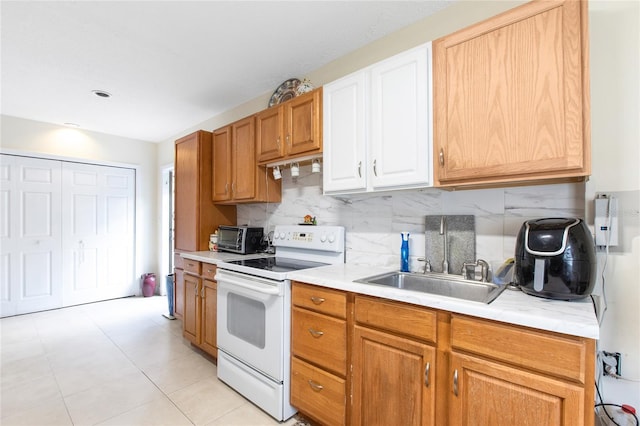 kitchen featuring a sink, tasteful backsplash, light countertops, and white range with electric cooktop