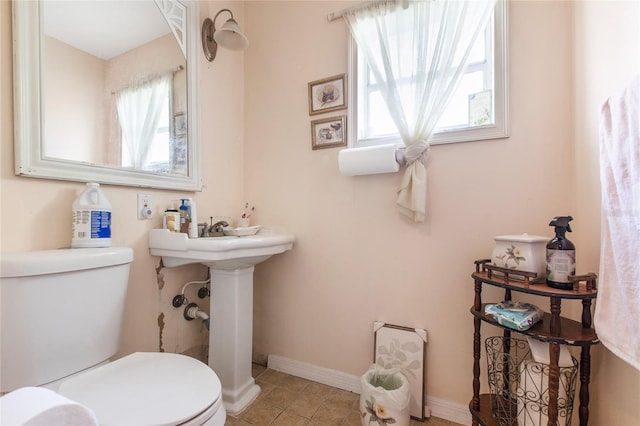 half bathroom featuring toilet, baseboards, and tile patterned floors