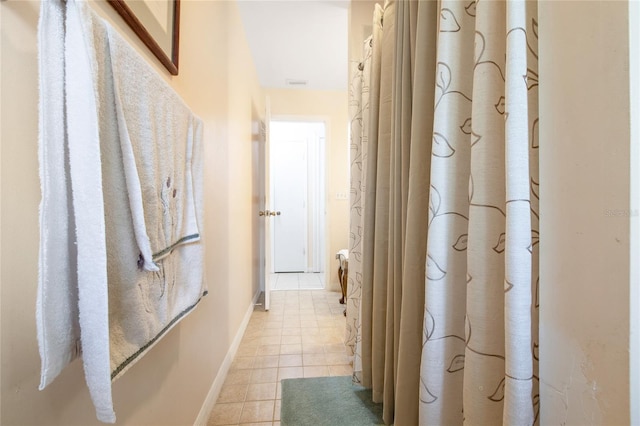 hall featuring light tile patterned flooring and baseboards