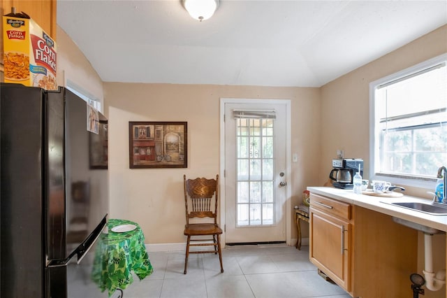 interior space featuring lofted ceiling, light tile patterned floors, a sink, and baseboards