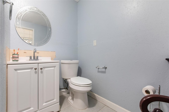 half bath with toilet, vanity, baseboards, and tile patterned floors