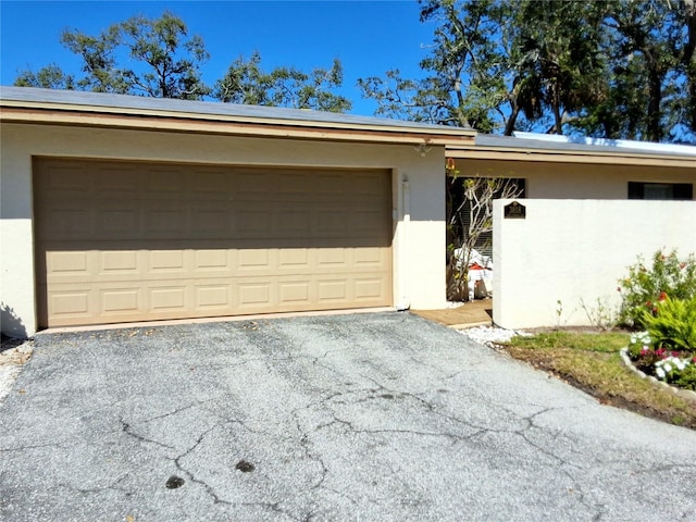 view of front facade with aphalt driveway, an attached garage, and stucco siding