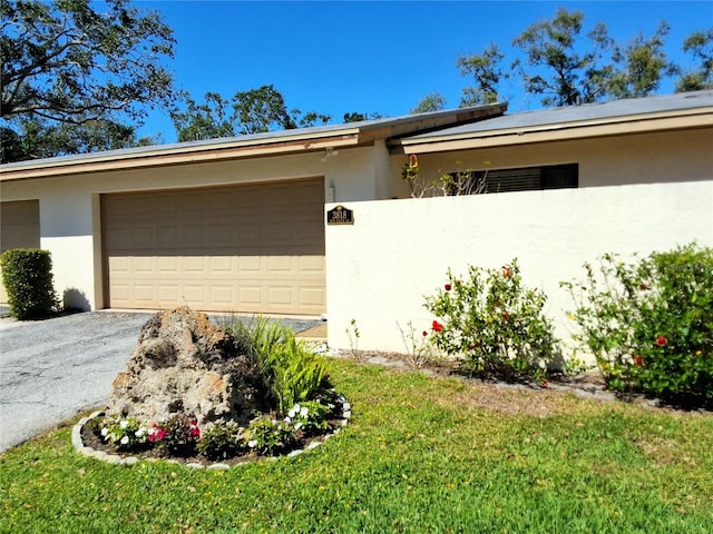 view of front facade featuring a garage, aphalt driveway, and stucco siding