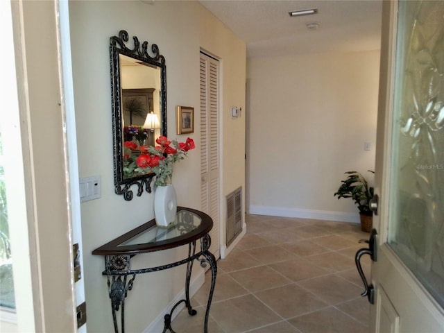 hallway with tile patterned flooring, visible vents, and baseboards