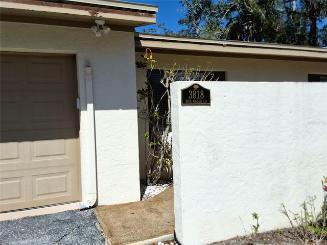 entrance to property featuring a garage and stucco siding