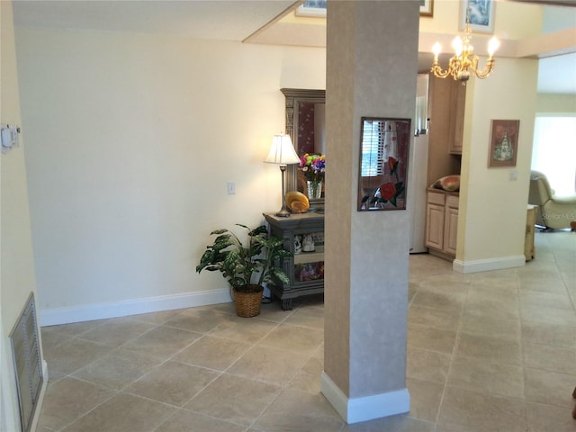 corridor featuring visible vents, a notable chandelier, baseboards, and light tile patterned floors