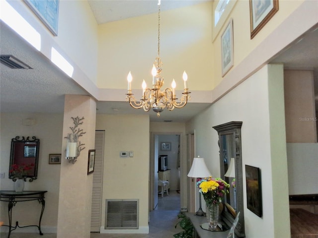 hall with a towering ceiling, visible vents, and a chandelier