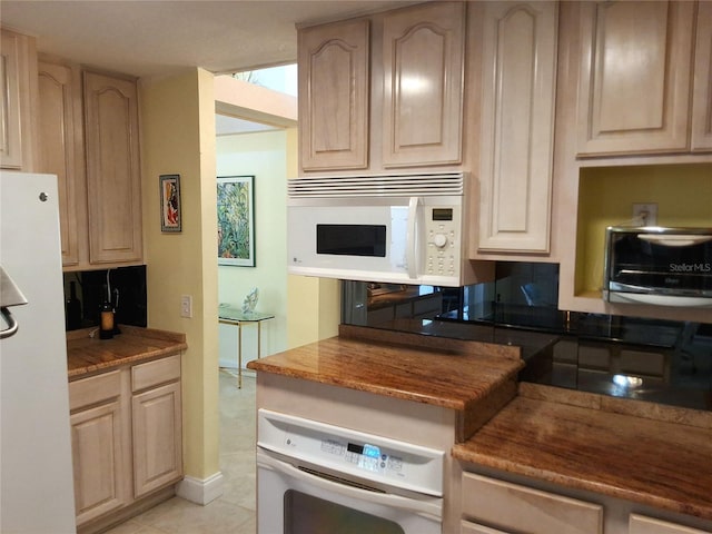 kitchen with white appliances, a toaster, light tile patterned flooring, and light brown cabinetry