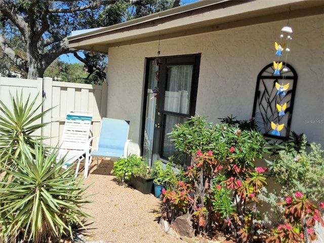 doorway to property with fence and stucco siding