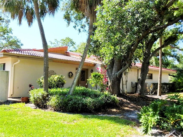 3818 Sun Eagle Ln, Bradenton, FL 34210 - view of property exterior with a tiled roof, a yard, and stucco siding
