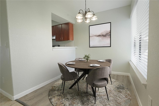 dining space with a notable chandelier, light wood-style floors, and baseboards