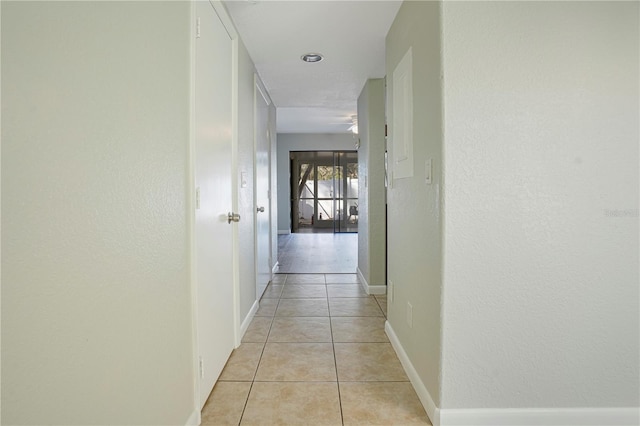 hallway with light tile patterned flooring and baseboards