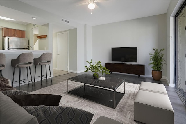 living room with light wood-type flooring, visible vents, and baseboards