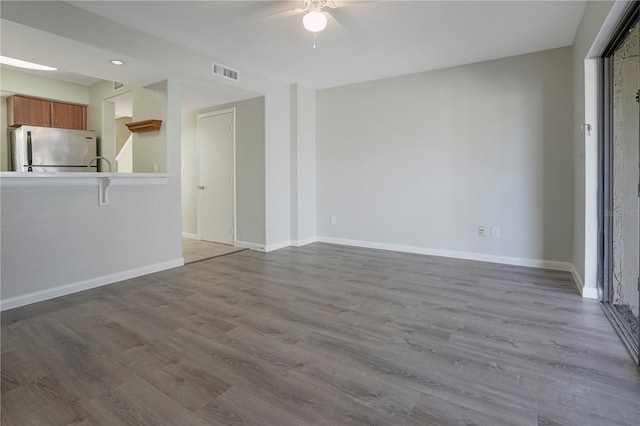 unfurnished living room featuring baseboards, visible vents, ceiling fan, and wood finished floors