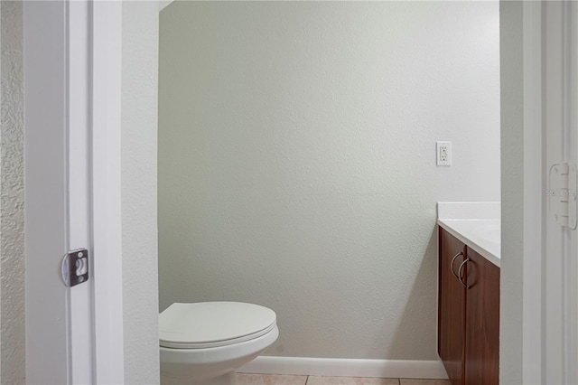 half bathroom featuring toilet, baseboards, vanity, and tile patterned floors