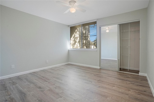 unfurnished bedroom with a closet, wood finished floors, a ceiling fan, and baseboards