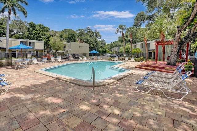 community pool with a patio and fence