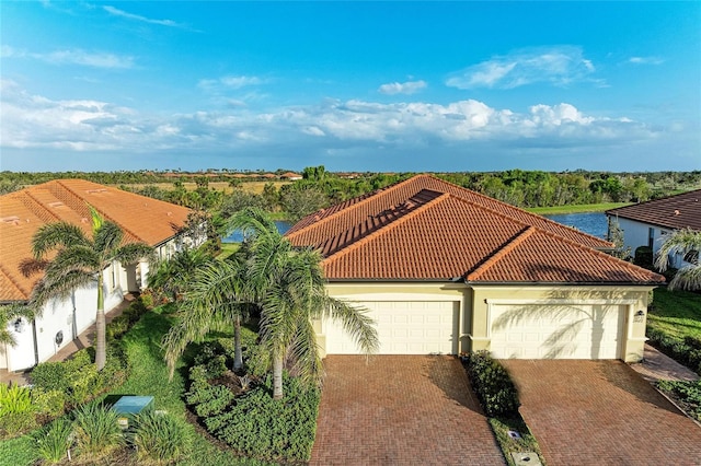 view of front of property featuring decorative driveway, a tile roof, an attached garage, and stucco siding