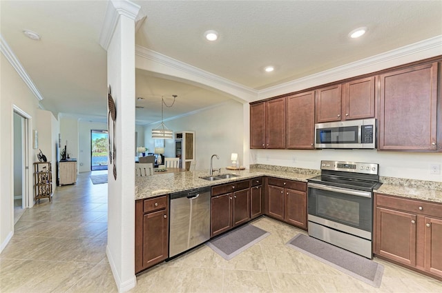 kitchen featuring decorative columns, light stone counters, stainless steel appliances, crown molding, and a sink