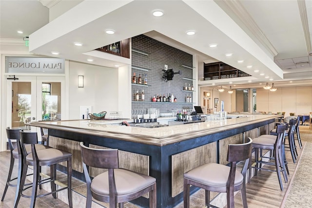 bar featuring light wood-style flooring, ornamental molding, wet bar, french doors, and recessed lighting