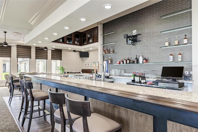 bar featuring recessed lighting, wood finished floors, a community bar, a ceiling fan, and tasteful backsplash