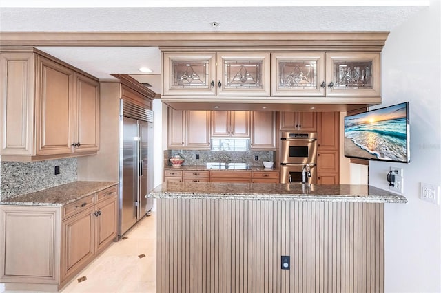 kitchen with a peninsula, backsplash, light stone countertops, and appliances with stainless steel finishes