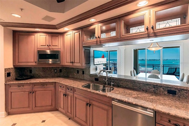 kitchen with a sink, backsplash, recessed lighting, appliances with stainless steel finishes, and light stone countertops