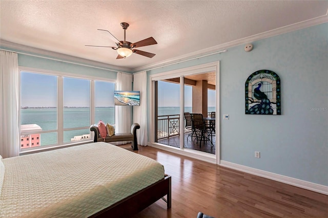 bedroom featuring access to outside, a textured ceiling, wood finished floors, crown molding, and baseboards