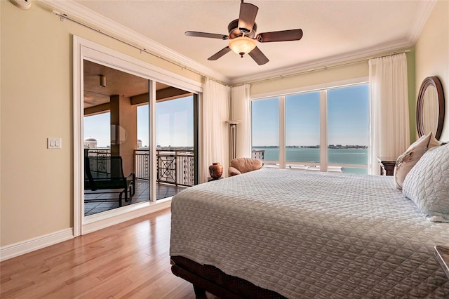 bedroom with wood finished floors, baseboards, ornamental molding, access to exterior, and a water view