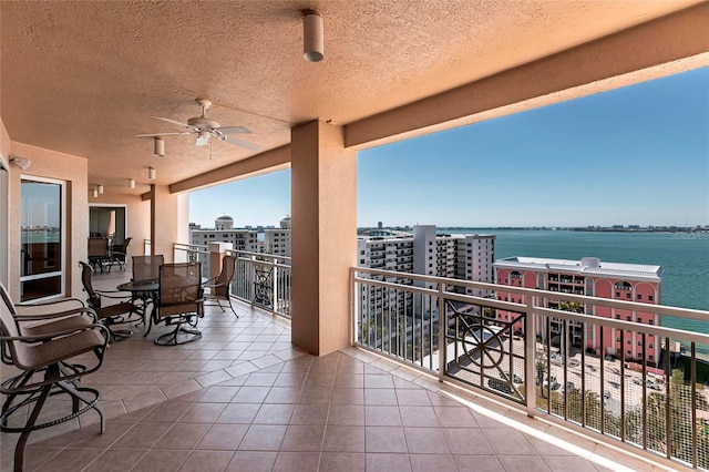 balcony featuring a city view, a water view, and ceiling fan