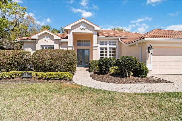 mediterranean / spanish-style house with a tiled roof, french doors, an attached garage, and stucco siding