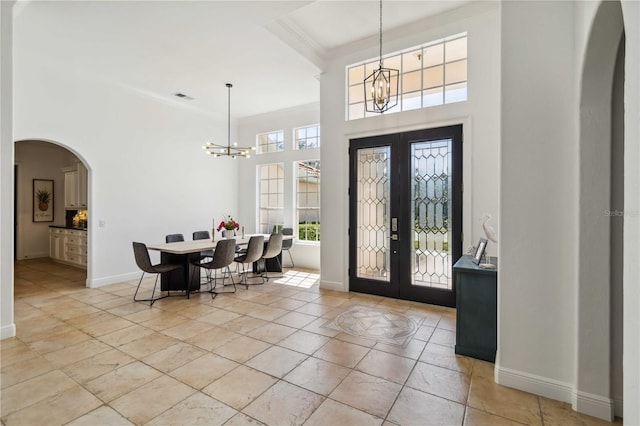 foyer entrance featuring a chandelier, arched walkways, ornamental molding, and baseboards