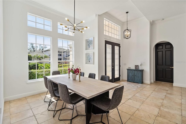 dining room with a chandelier, ornamental molding, arched walkways, and baseboards