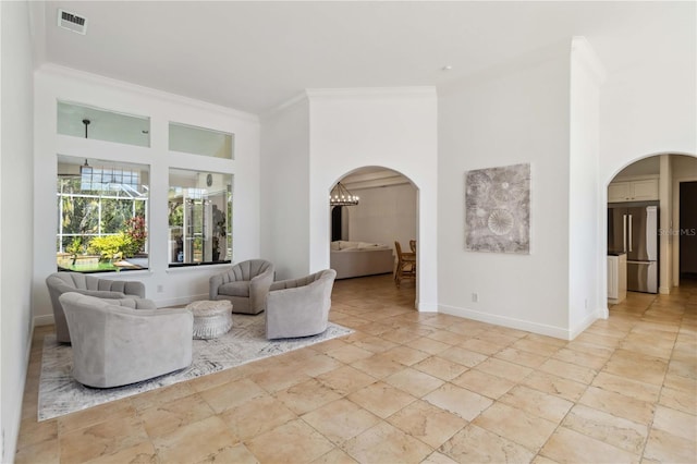 living room featuring arched walkways, ornamental molding, and baseboards