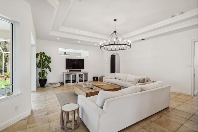 living area with ornamental molding, arched walkways, and a raised ceiling