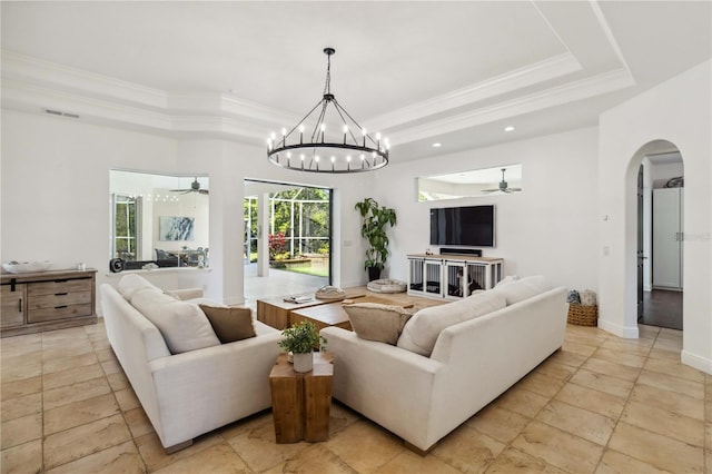 living area featuring arched walkways, visible vents, baseboards, ornamental molding, and a tray ceiling