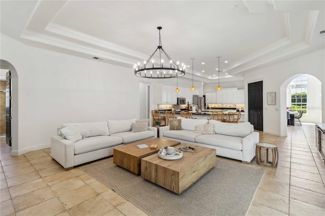 living room with crown molding, arched walkways, and a tray ceiling