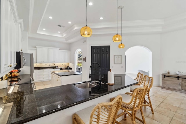 kitchen with arched walkways, a sink, ornamental molding, appliances with stainless steel finishes, and a tray ceiling