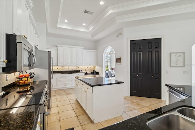 kitchen featuring a raised ceiling, visible vents, appliances with stainless steel finishes, ornamental molding, and white cabinets