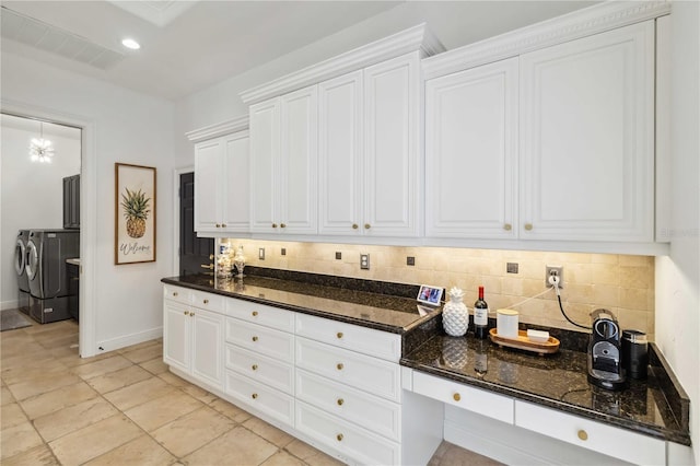 kitchen with tasteful backsplash, visible vents, washer and clothes dryer, dark stone counters, and white cabinetry