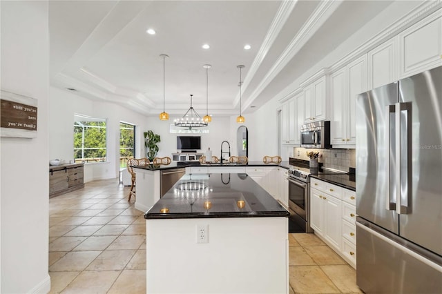 kitchen with a raised ceiling, appliances with stainless steel finishes, a peninsula, white cabinetry, and a sink