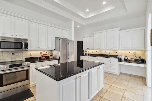 kitchen featuring white cabinets, a raised ceiling, decorative backsplash, a kitchen island, and appliances with stainless steel finishes