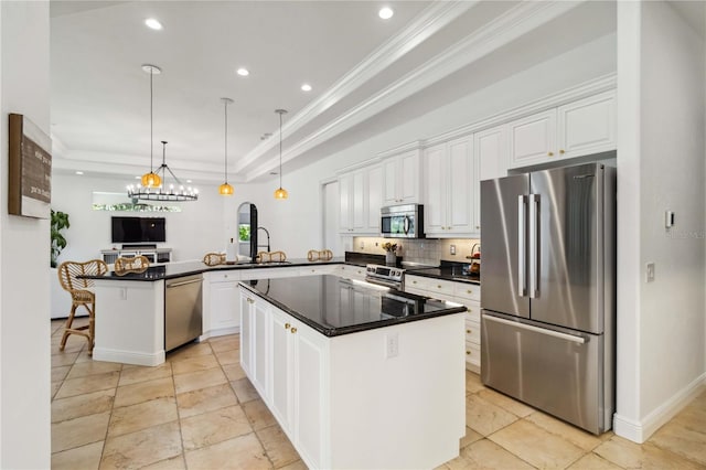 kitchen featuring dark countertops, a peninsula, a tray ceiling, stainless steel appliances, and white cabinetry