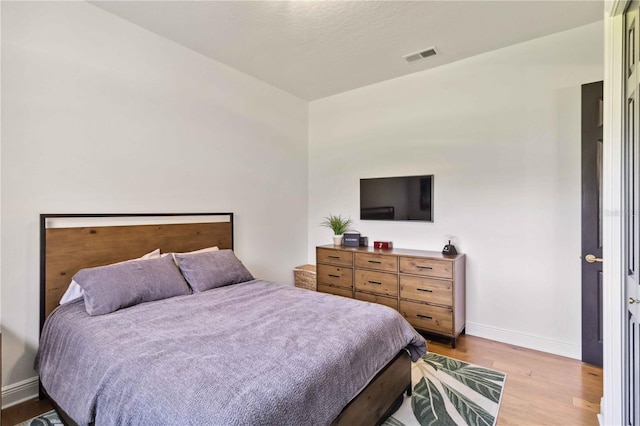 bedroom featuring visible vents, baseboards, and wood finished floors