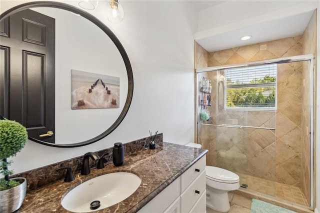 bathroom featuring vanity, a shower stall, and toilet