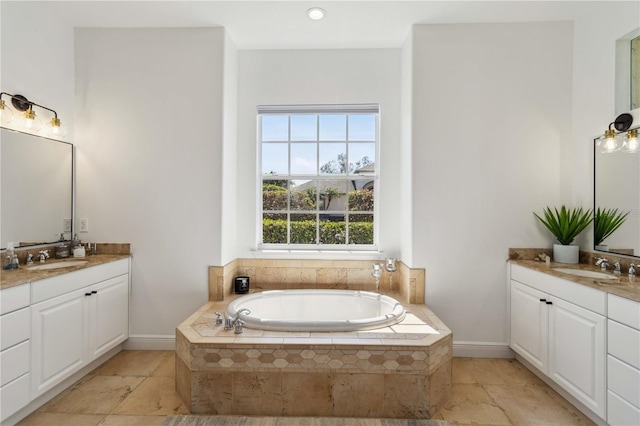 full bath with a sink, two vanities, a bath, and baseboards