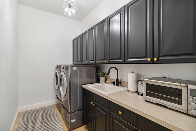 clothes washing area featuring a toaster, cabinet space, a sink, separate washer and dryer, and baseboards